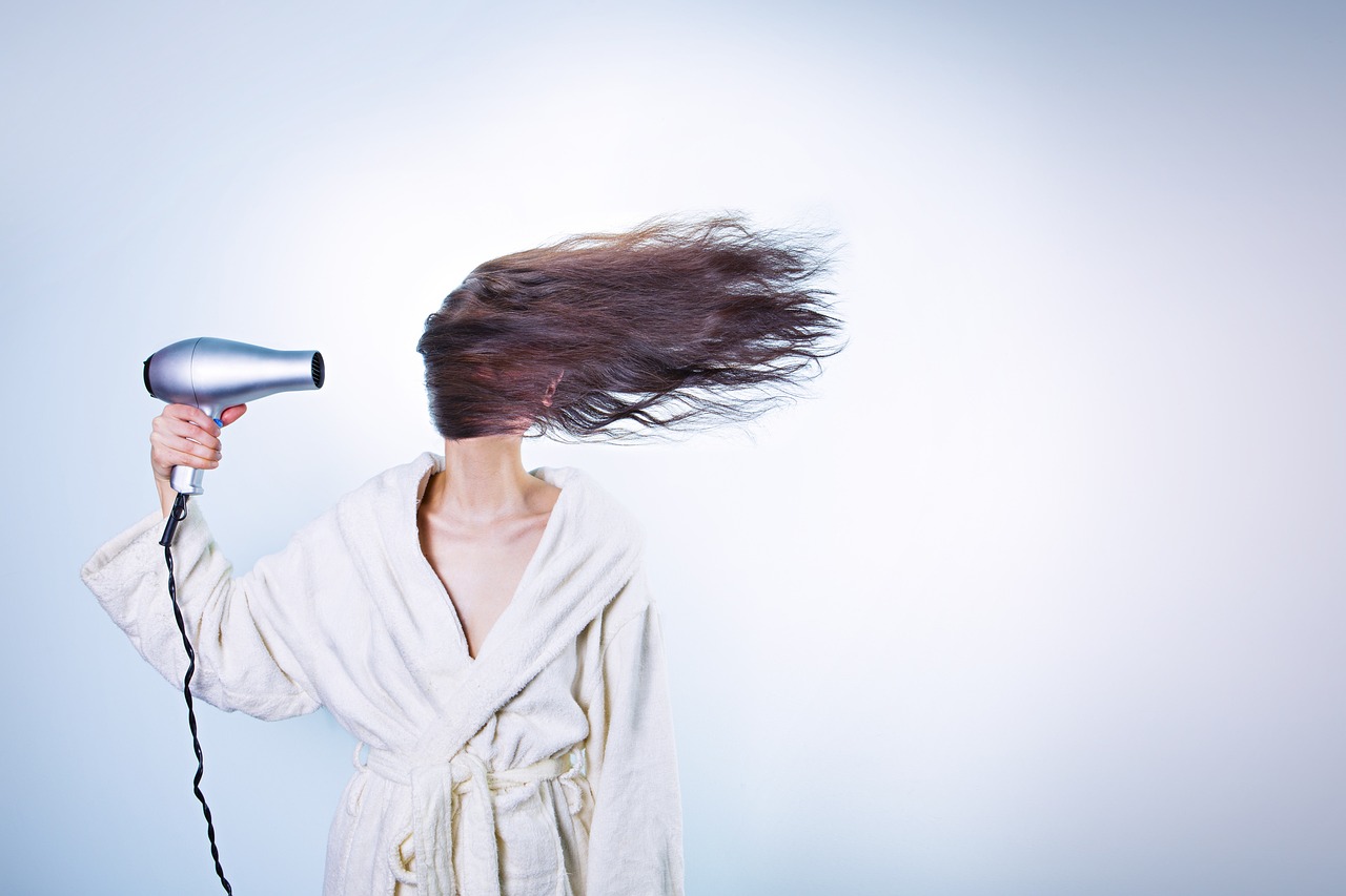 Phon acceso mentre asciuga i capelli, evidenziando l'errore comune che li danneggia.