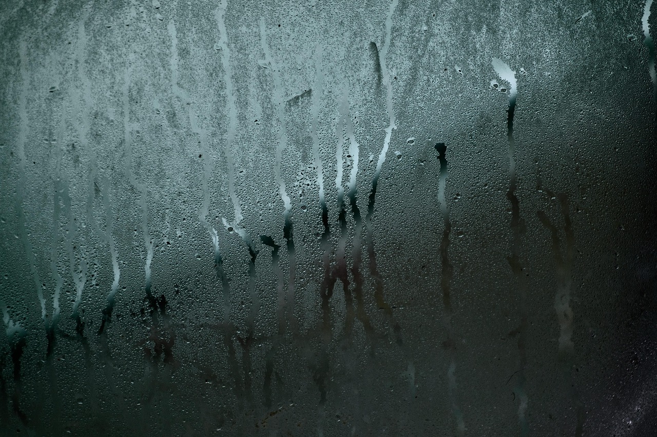 Specchio del bagno appannato con riflesso di un uomo che asciuga la superficie.