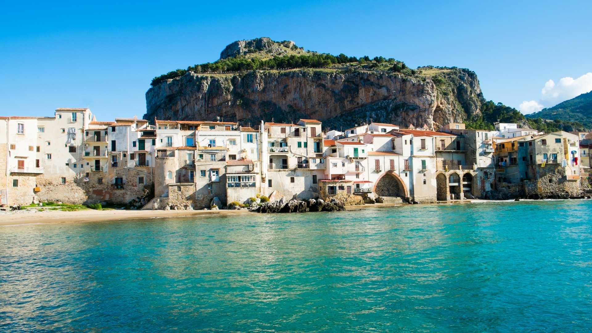 Panorama di un pittoresco borgo italiano su un'isola, con case colorate e mare cristallino.